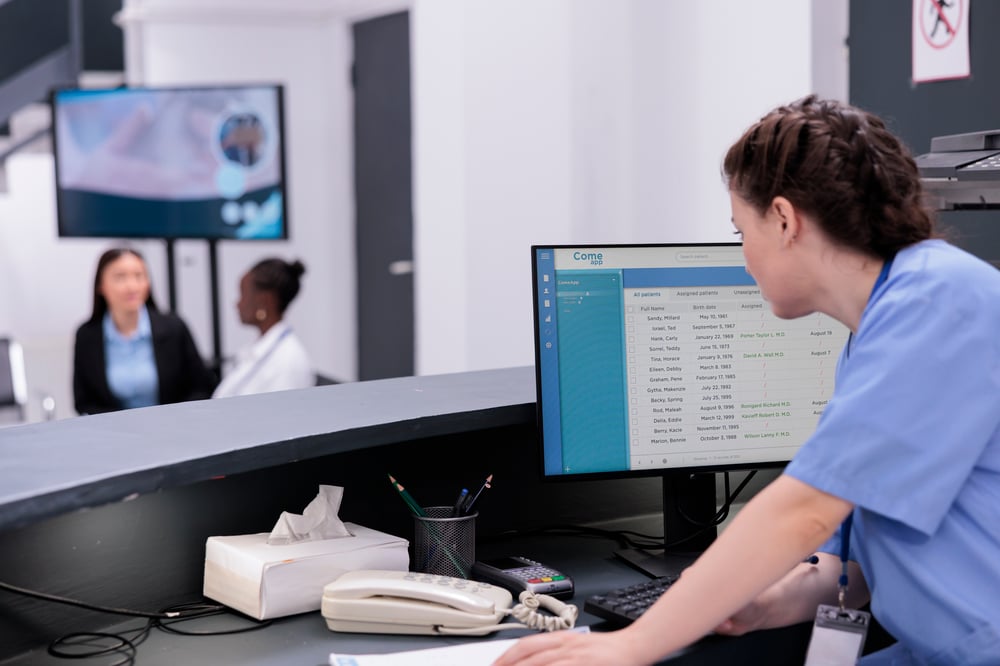 assistant-looking-patients-checkup-appointments-computer-while-checking-medical-expertise-papers-working-patient-treatment-hospital-waiting-area-medicine-service-concept