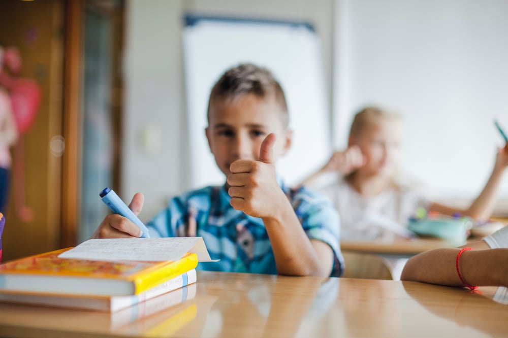 boy-sitting-school-desk-gesturing