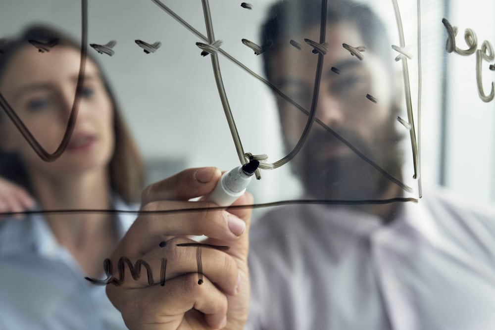 close-up-man-explaining-business-analytics-his-female-colleague-with-graph-whiteboard