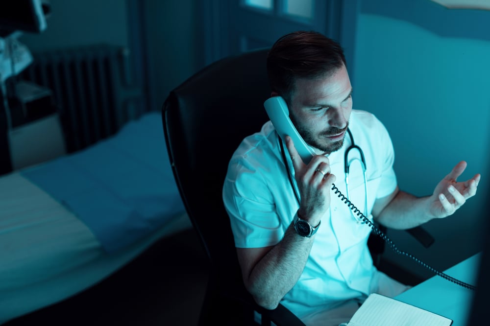 male-doctor-sitting-hospital-talking-someone-phone