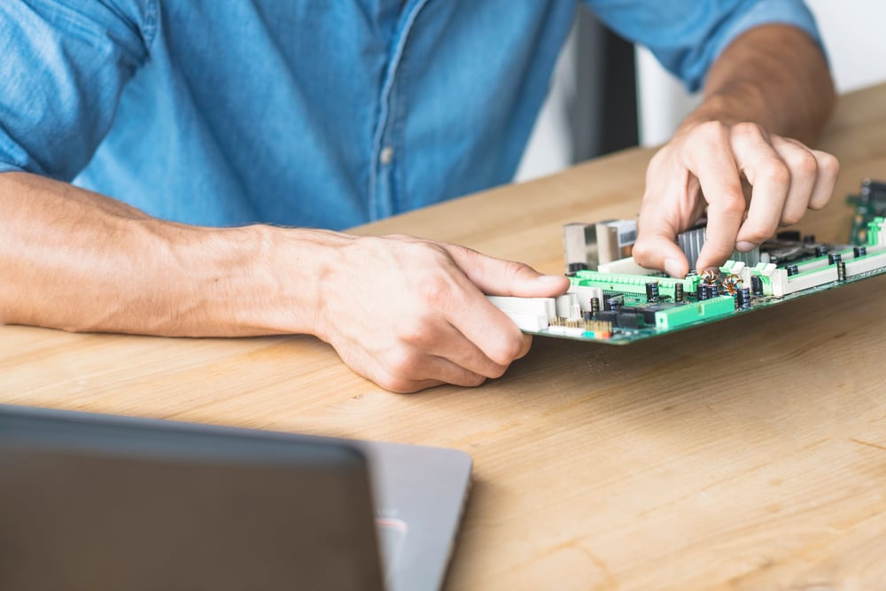 male-technician-repairing-motherboard-workbench