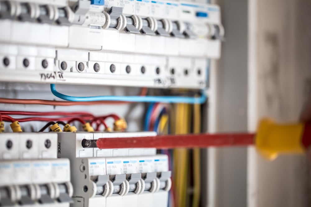 man-electrical-technician-working-switchboard-with-fuses-installation-connection-electrical-equipment-close-up