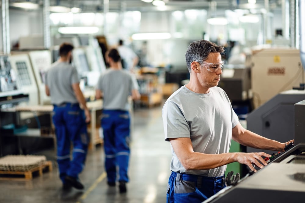 mid-adult-worker-operating-cnc-machine-while-working-industrial-facility (1)