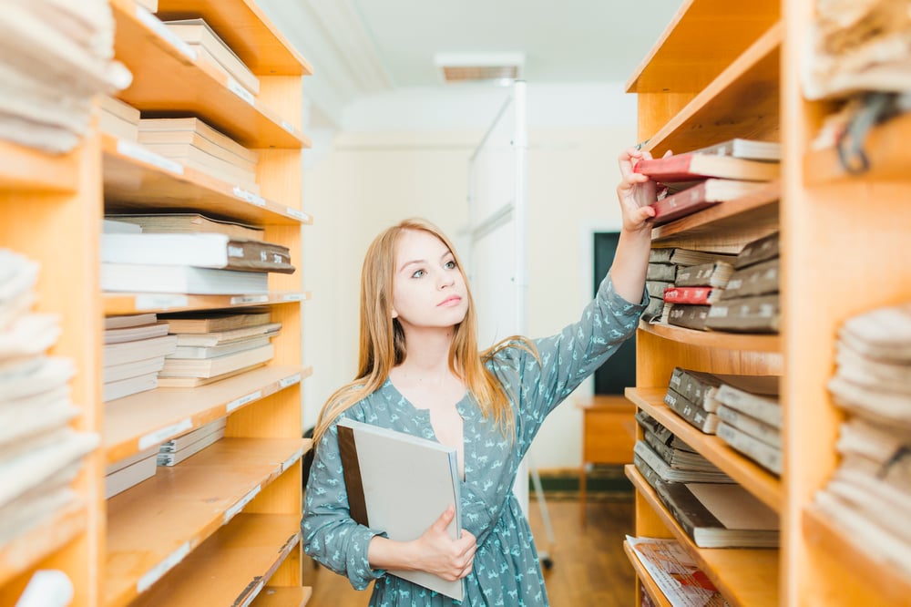 pretty-teenager-taking-textbooks-from-shelf