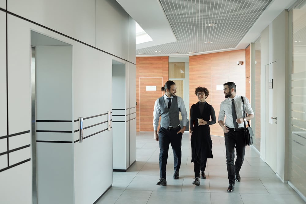 three-young-cheerful-colleagues-formalwear-chatting-their-way-office-while-passing-by-elevator-after-coffee-break