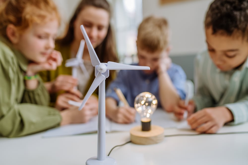 young-teacher-with-model-wind-turbine-learning-pupils-about-wind-energy